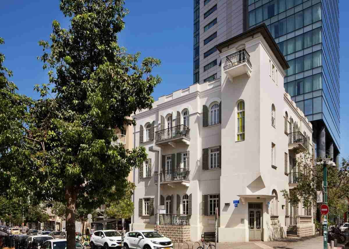 בניין בכר האוס בתל אביב לצד מגדל מודרני מזכוכית ברקע