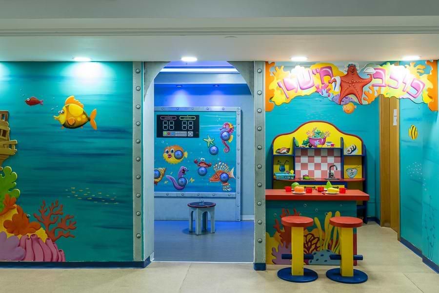 חדר משחקים צבעוני עם איורים ימיים ועמדות יצירה