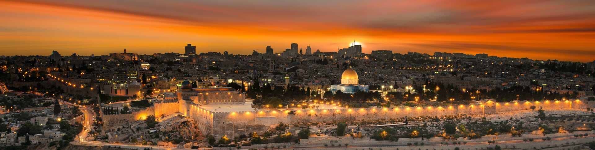 תמונה פנורמית של העיר העתיקה בירושלים בשעת השקיעה, עם כיפת הזהב הזוהרת במרכז וחומות העיר מאורות