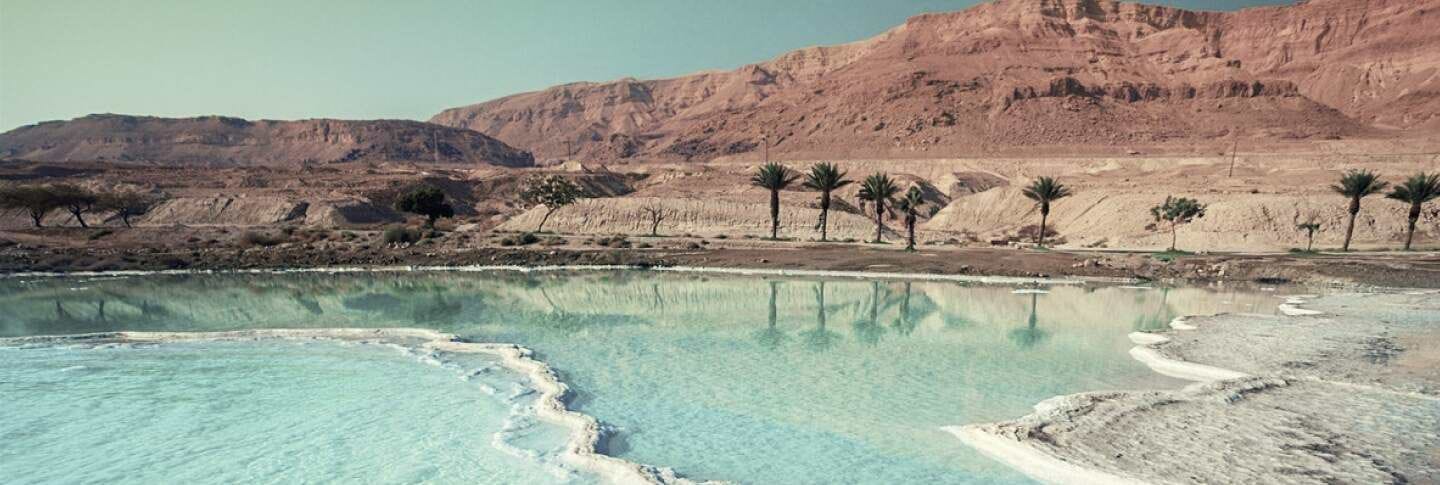 נוף מרהיב של ים המלח, עם מי תכלת עשירים במינרלים וגבישי מלח לבנים לאורך קו החוף